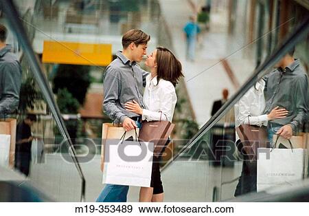 Stock Photo - Couple with shopping bags on scalator in shopping mall. Fotosearch