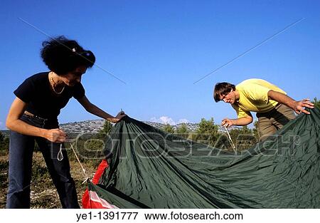 Couple working together to set up their tent at their campsite View Large Photo Image Stock Photo - Couple working together to set up their tent at their campsite. Fotosearch