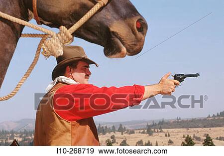 Stock Photo - Cowboy with horse aiming with a pistol. Oregon. USA. Fotosearch