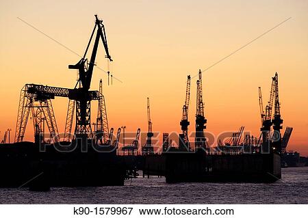 Cranes of the dockyards as black silhouettes against the orange sky after sunset with the river Elbe in the foreground, Hamburg, Germany, Europe View Large Photo Image Stock Photo - Cranes of the dockyards as black silhouettes against the orange sky after sunset with the river Elbe in the foreground, Hamburg, Germany, Europe. Fotosearch