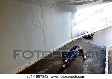 Stock Image - Crime scene concept photo of a murder victim woman lying dead on the ground of a tunnel.. Fotosearch