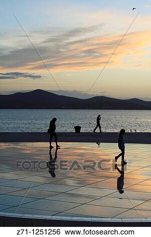Stock Photograph - Croatia, Zadar, sunset, people, Greeting to the Sun monument,. Fotosearch