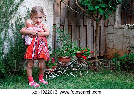 Cross female toddler with her doll in a garden Model release available View Large Photo Image Stock Image - Cross female toddler with her doll in a garden Model release available. Fotosearch