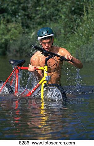 Stock Photograph - Crossing a river with a mountain bike. Fotosearch