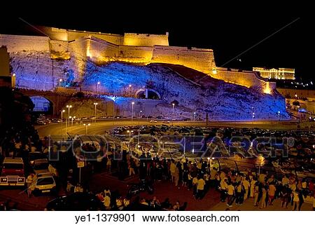 Crowd lining the streets surrounding Fort Saint-Nicholas illuminated at night with view of Pharo Palace in the distance, Marseille, France View Large Photo Image Stock Image - Crowd lining the streets surrounding Fort Saint-Nicholas illuminated at night with view of Pharo Palace in the distance, Marseille, France. Fotosearch