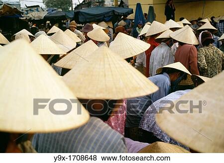 Stock Photo - Crowds of people wearing conical bamboo hats at a wet market for fresh fish in Vietnam The people come to buy and sell freshly caught fish from the sea. Fotosearch