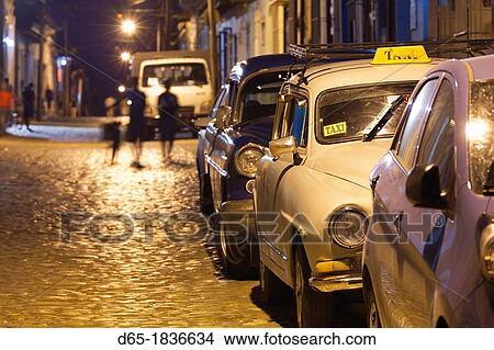 Cuba, Sancti Spiritus Province, Trinidad, taxis on Calle Antonio Maceo, dusk View Large Photo Image Picture - Cuba, Sancti Spiritus Province, Trinidad, taxis on Calle Antonio Maceo, dusk. Fotosearch