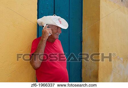 Cuba Trinidad local cowboy with hat against yellow wall on cell phone communicating of old downtown building. View Large Photo Image Stock Photo - Cuba Trinidad local cowboy with hat against yellow wall on cell phone communicating of old downtown building.. Fotosearch