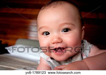 Stock Image - Curious and smiling baby girl. Fotosearch