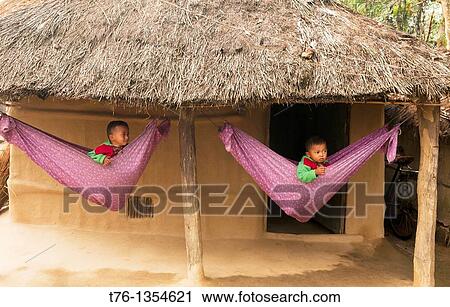 Stock Image - cute boys in hammocks in a Tharu village in Chitwan National Park in Nepal. Fotosearch