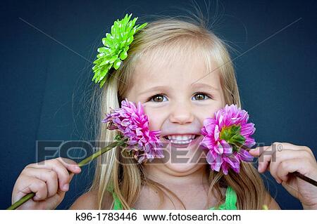 Stock Photograph - cute little girl with flowers looking at camera. Fotosearch