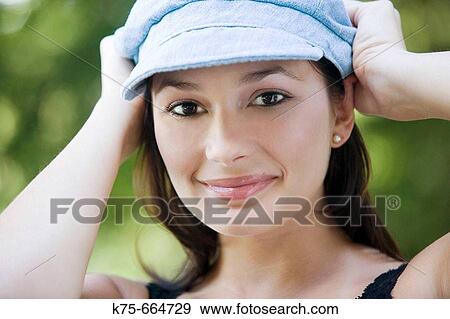 Stock Photo - Cute woman with hands on her cap. Fotosearch