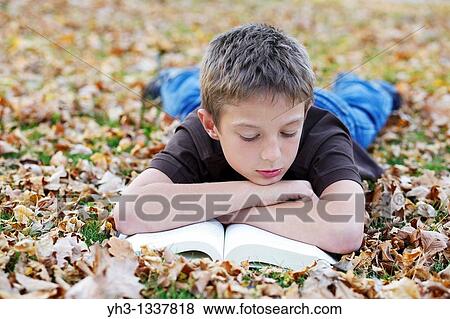 Cute young boy reading children book outdoor View Large Photo Image Stock Photo - Cute young boy reading children book outdoor. Fotosearch