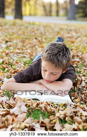 Cute young boy reading children book outdoor View Large Photo Image Stock Photo - Cute young boy reading children book outdoor. Fotosearch