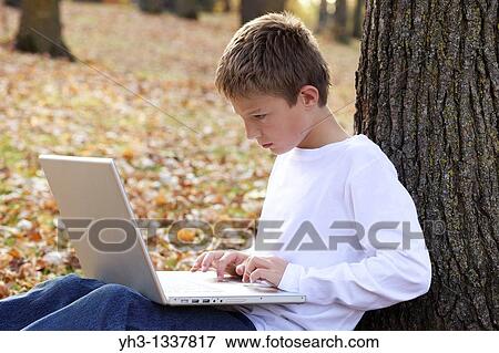 Cute young boy using a laptop outdoor View Large Photo Image Stock Photo - Cute young boy using a laptop outdoor. Fotosearch