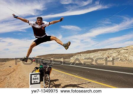 Cyclist jumping by the 666 km distance bollard on the side of Sudanese road View Large Photo Image Stock Photography - Cyclist jumping by the 666 km distance bollard on the side of Sudanese road. Fotosearch