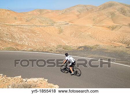 Stock Photo - Cyclist on mountain road on Fuerteventura, Canary Islands, Spain. Fotosearch