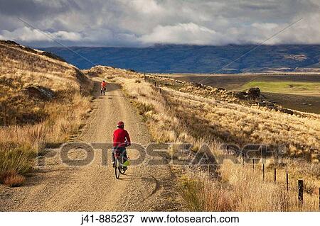 Stock Photo - Cyclists on Otago Rail Trail near Oturehua, Central Otago, New Zealand. Fotosearch