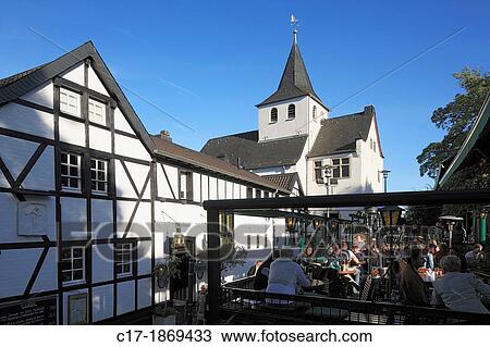 D-Cologne, Rhine, Rhineland, North Rhine-Westphalia, NRW, D-Cologne-Rodenkirchen, church Alt St Maternus, chapel, catholic church, Romanesque style, old ferry house, restaurant, guesthouse Zum Treppchen, people sitting in a sidewalk restaurant View Large Photo Image Stock Image - D-Cologne, Rhine, Rhineland, North Rhine-Westphalia, NRW, D-Cologne-Rodenkirchen, church Alt St Maternus, chapel, catholic church, Romanesque style, old ferry house, restaurant, guesthouse Zum Treppchen, people sitting in a sidewalk restaurant. Fotosearch