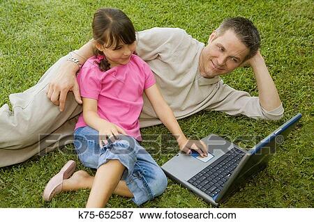 Stock Photo - Dad and daughter using laptop outdoors. Fotosearch