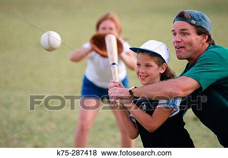 Stock Photo - dad coaching his daughter at bat. Fotosearch
