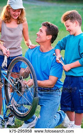 Stock Photo - Dad, daughter, and son repairing bike. Fotosearch