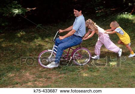 Dad gets help on kids bike View Large Photo Image Stock Photo - Dad gets help on kids bike. Fotosearch
