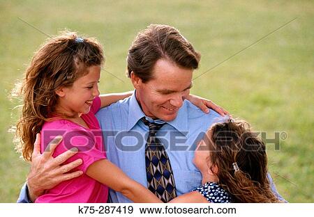 dad gets hugs from his daughters View Large Photo Image Stock Photo - dad gets hugs from his daughters. Fotosearch