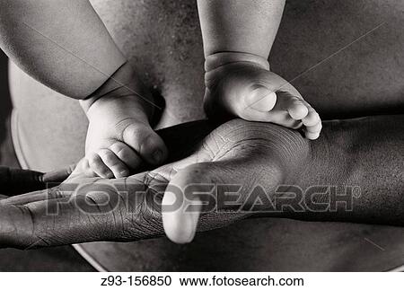 Dad holds baby son's feet in his hand View Large Photo Image Stock Image - Dad holds baby son's feet in his hand. Fotosearch