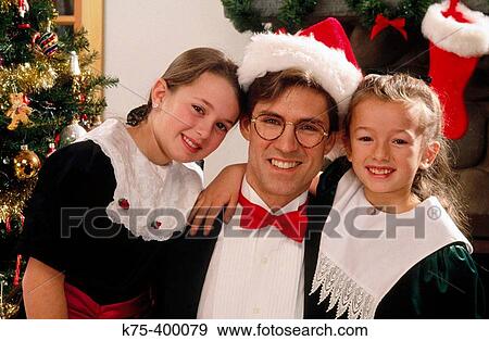 Stock Photo - Dad hugging two daughters at Christmas. Fotosearch