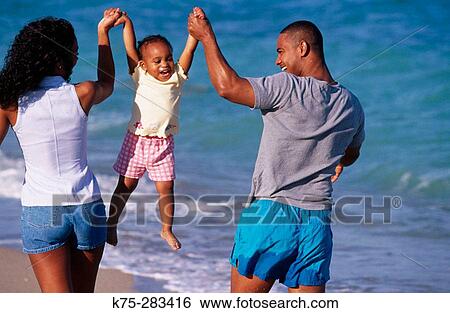 Dad, mom, and daughter enjoying the beach View Large Photo Image Stock Photograph - Dad, mom, and daughter enjoying the beach. Fotosearch