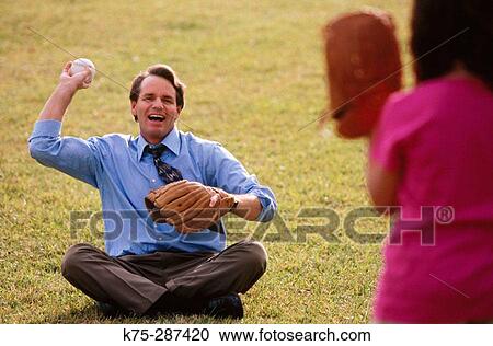 Stock Image - dad playing baseball with his daughter after work. Fotosearch