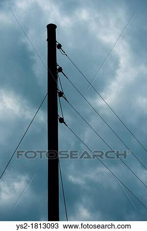 Stock Image - Dark sky with heavy clouds and wooden telephone mast with phone lines. Fotosearch