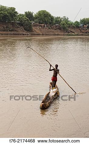 Stock Photo - Dassanech man rowing his dugout canoe on the Omo River in the Lower Omo Valley of Ethiopia.. Fotosearch