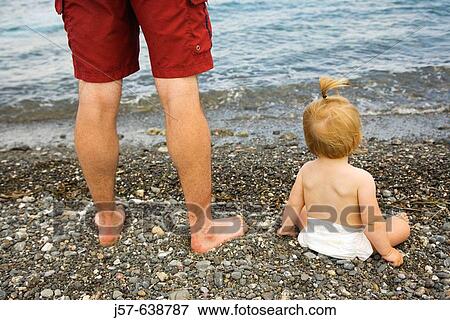 Daughter and father looking out into the ocean on a gravel beach in Kos Island. Greece. View Large Photo Image Stock Photo - Daughter and father looking out into the ocean on a gravel beach in Kos Island. Greece.. Fotosearch