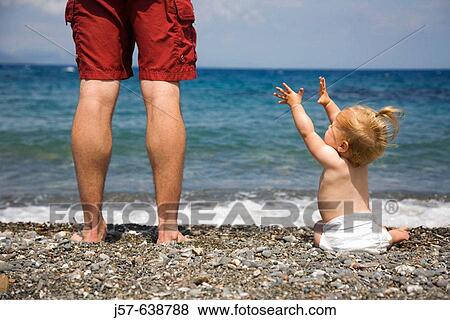 Daughter and father looking out into the ocean on a gravel beach in Kos Island. Greece. Daughter reaching for father View Large Photo Image Stock Photo - Daughter and father looking out into the ocean on a gravel beach in Kos Island. Greece. Daughter reaching for father. Fotosearch