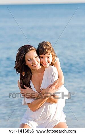 Daughter giving a hug to her mother in the seashore at the beach View Large Photo Image Stock Photograph - Daughter giving a hug to her mother in the seashore at the beach. Fotosearch