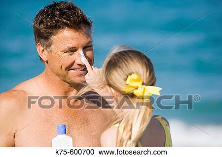 Stock Image - Daughter putting sunscreen on dad's nose. Fotosearch