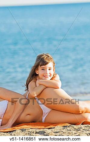 Daughter with mother smiling at camera at the beach View Large Photo Image Stock Image - Daughter with mother smiling at camera at the beach. Fotosearch