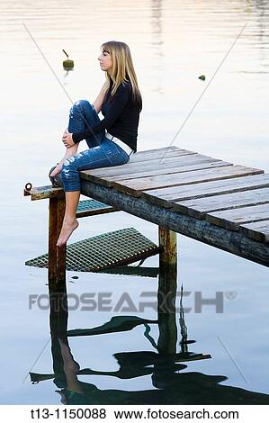 Daydreaming young woman on an old wooden pier View Large Photo Image Stock Photo - Daydreaming young woman on an old wooden pier. Fotosearch