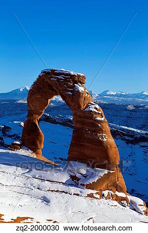 Stock Image - Delicate Arch with snow in winter at sunset, Arches National Park, Utah, United States of America.. Fotosearch