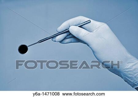 Dentist in surgical gloves holding angled mirror View Large Photo Image Stock Photo - Dentist in surgical gloves holding angled mirror. Fotosearch