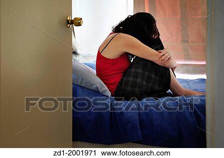 Depressed young woman sitting on the bed at home suffering from a severe depression. View Large Photo Image Stock Image - Depressed young woman sitting on the bed at home suffering from a severe depression.. Fotosearch