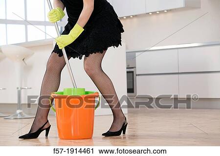 Stock Image - Detail of a sexy young woman mopping the kitchen in high heels and rubber gloves. Fotosearch