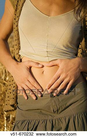 Detail of a young woman drawing a heart on her belly with her hands View Large Photo Image Stock Image - Detail of a young woman drawing a heart on her belly with her hands. Fotosearch