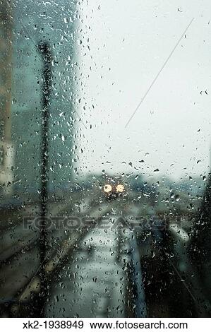 Stock Photo - Detail of drops in a rainy day and a train approaching to the station DLR, Canary Wharf, London, UK. Fotosearch