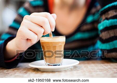 Detail of woman's hand mixing latte coffee with a spoon View Large Photo Image Stock Photo - Detail of woman's hand mixing latte coffee with a spoon. Fotosearch
