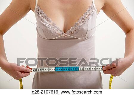 Detail of Young beautiful woman in pink underwear, measuring her waistline with a measuring tape, concept photo View Large Photo Image Stock Photograph - Detail of Young beautiful woman in pink underwear, measuring her waistline with a measuring tape, concept photo. Fotosearch