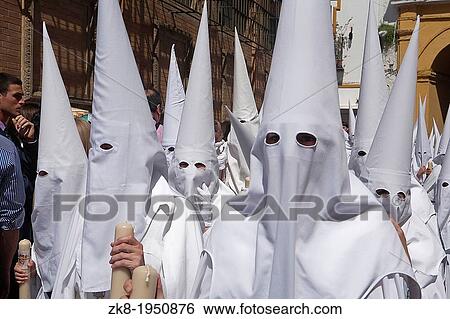 Stock Photograph - Detail penitent white holding a candle during Holy Week, Spain.. Fotosearch