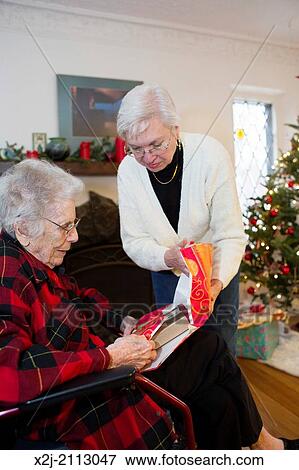 Stock Photo - Detroit, Michigan - 99 years old woman opens a Christmas present with the help of her daughter (65). Fotosearch